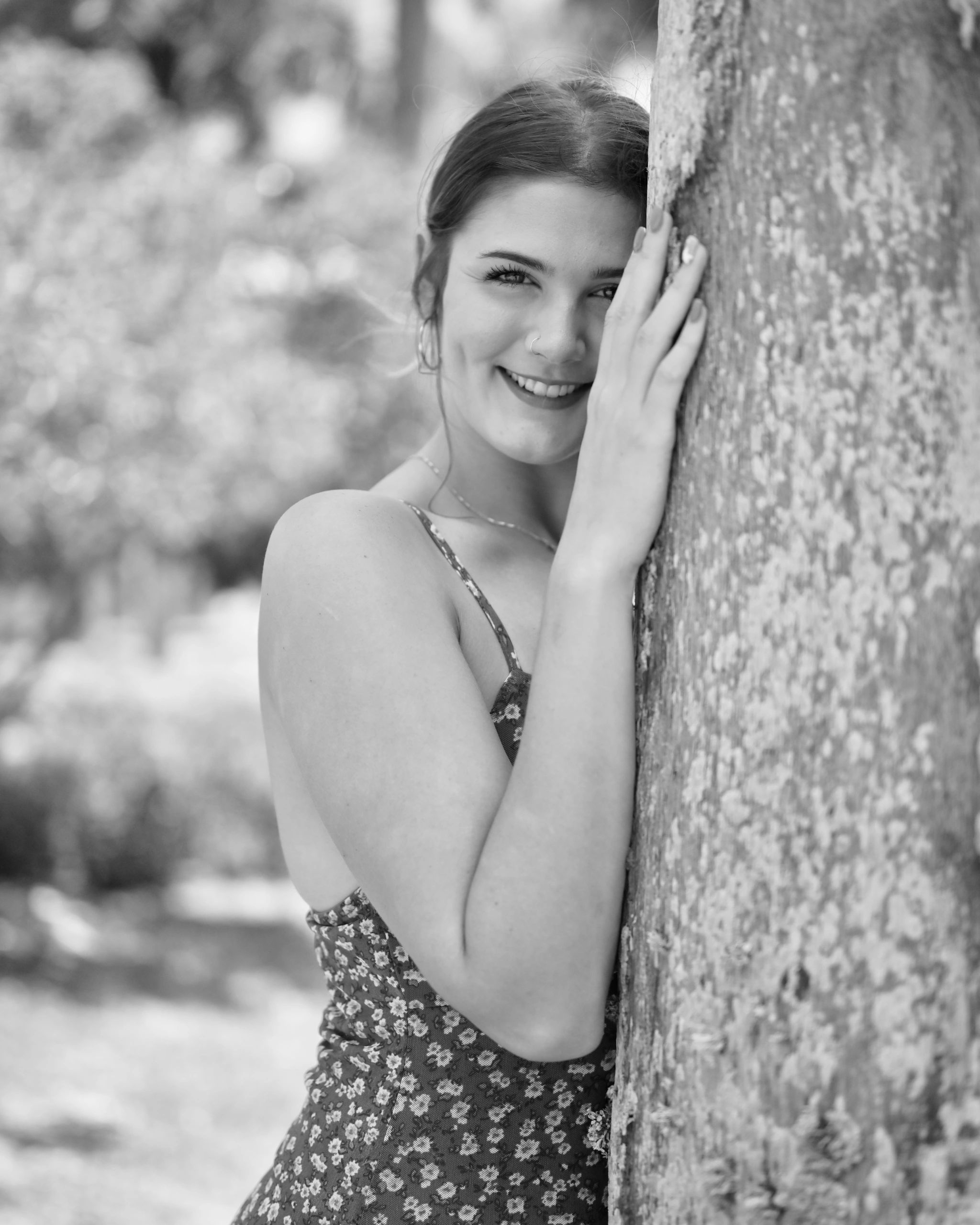 Smiling woman leaning against a tree in a black-and-white portrait