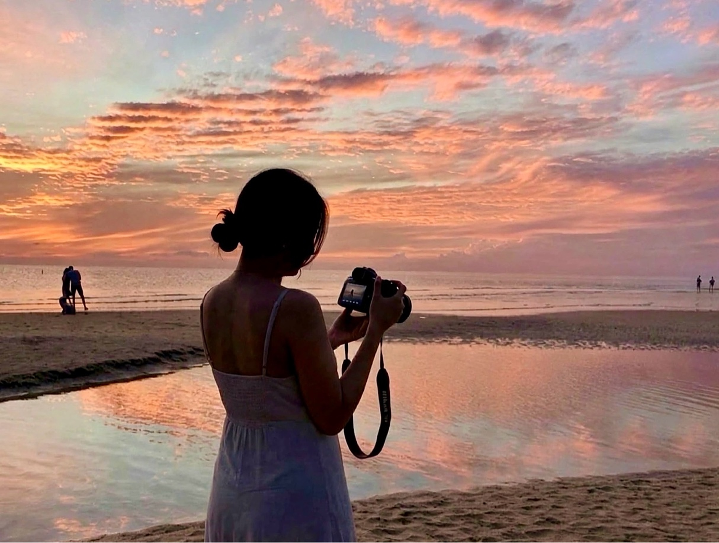 Photographer holding her camera on the Naples beach at sunset